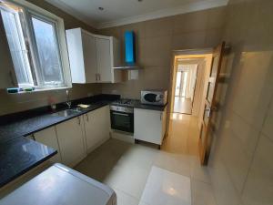 una pequeña cocina con armarios blancos y fregadero en Private Room- Direct Travel Central/ Heathrow en Londres