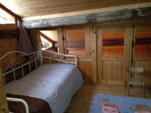 1 dormitorio en una cabaña de madera con 1 cama y 1 silla en La Marguerite, en Aigueblanche