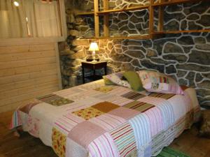 a bedroom with a bed and a stone wall at La Marguerite in Aigueblanche