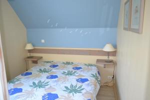 um pequeno quarto com uma cama com uma parede azul em La Maison Rose em Fort-Mahon-Plage