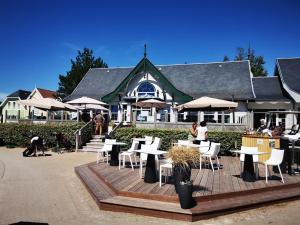 a restaurant with tables and chairs and a building at La Maison Rose in Fort-Mahon-Plage