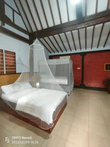 a bedroom with a bed with a mosquito net at jala sutra cottages in Giri