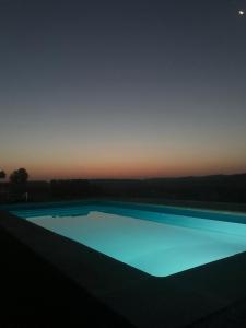 uma piscina azul à noite com o céu em Cabezo Buñuel Hostal em Calanda