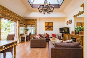 sala de estar con lámpara de araña y sofá en The Coach House by Bloom Stays, en Harrietsham