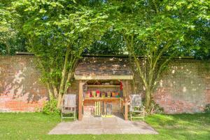 a brick building with two chairs and a table with books at The Coach House by Bloom Stays in Harrietsham