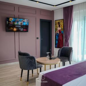 a living room with a table and chairs and a tv at Jata Crown Hotel in Tirana