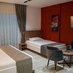 a bedroom with two beds and a table and a chair at Jata Crown Hotel in Tirana