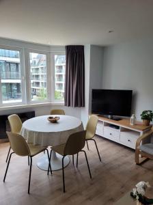a living room with a table and chairs and a television at 1 slaapkamer logie met extra zetelbed in leefruimte in Middelkerke