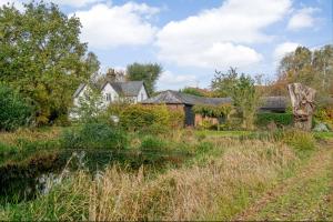 a house in the middle of a field with a pond at Available For Contractors 2 Double Beds and Sofa Bed Private Parking in Harlow