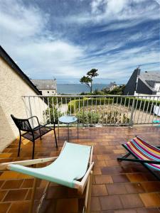 eine Terrasse mit Stühlen, einem Tisch und Meerblick in der Unterkunft Villa Simone vue mer 2min à pied de la plage in Saint-Lunaire