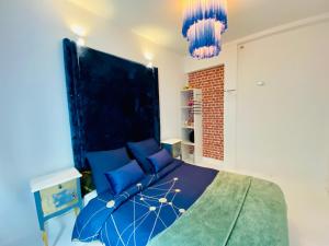 a bedroom with a blue bed and two chandeliers at Appartement Vert du Palais - Relaxation Centrale in Le Palais