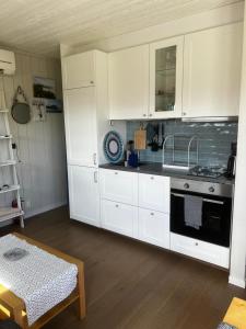 cocina con armarios blancos, fregadero y fogones en Fantastisk Vätterutsikt mellan Habo och Bankeryd. en Habo
