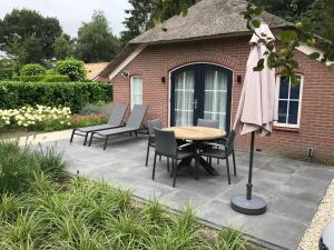 un patio con sillas, una mesa y una sombrilla en Villa Felix with sauna in Ermelo en Ermelo