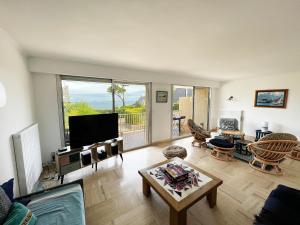 uma sala de estar com uma televisão de ecrã plano e uma mesa em Villa Simone vue mer 2min à pied de la plage em Saint-Lunaire
