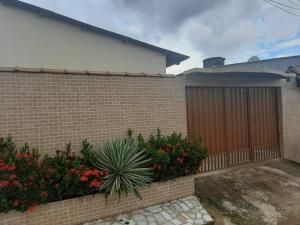 uma cerca de tijolo com um portão de madeira e flores em Apart Hotel M6D em Rio Branco