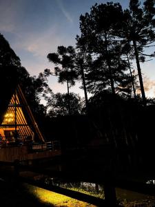 a cabin with a fence and trees at night at Cold Land Chalé in Urubici