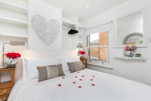 a white bedroom with a large bed with red hearts on the wall at The Nestle House in Winchester