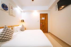 a bedroom with a white bed and a wooden door at Beach Breeze and Spa in Hulhumale