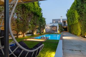 Luxury Villa Hestia Grey with Private Pool في مدينة ريثيمنو: حديقه خلفيه بها مسبح ومنزل