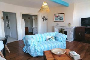 ein Wohnzimmer mit einem blauen Sofa und einem Tisch in der Unterkunft Le grand Houx in Orthez