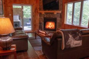 a living room with couches and a fireplace at Chalet L'Envolée near Tremblant in Saint-Faustin