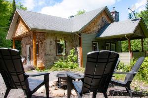 two chairs and a table in front of a house at Chalet L'Envolée near Tremblant in Saint-Faustin