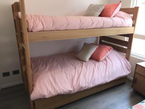 パプドにあるPrecioso departamento Papudo a pasos de la playaの二段ベッド2組(ピンクのシーツ付)が備わる客室です。