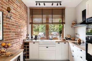 a kitchen with white cabinets and a brick wall at Grabowa 19 in Brzozówka