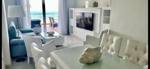ミハス・コスタにあるMI CAPRICHO C16 Beachfront Apartmentの白いリビングルーム(テーブル、椅子付)