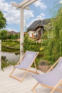 zwei Gartenstühle auf einer Terrasse mit einem Haus im Hintergrund in der Unterkunft Grabowa 19 in Brzozówka