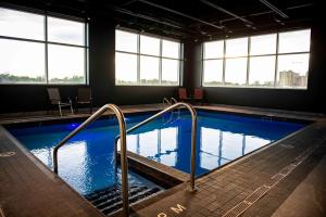 a large swimming pool with metal hand rails in a building at Grand Times Hotel Laval - Centropolis in Laval