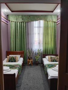 a room with two beds and a window with green curtains at House4you in Tashkent