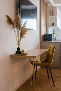 einen Esstisch mit einer Pflanze und einem gelben Stuhl in der Unterkunft SOLMAR Studio Sea View in Năvodari