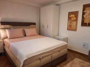 een slaapkamer met een groot wit bed met roze kussens bij El Sol Apartmani in Bar