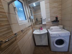 a small bathroom with a washing machine and a sink at El Sol Apartmani in Bar