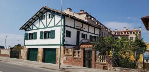 a white and green house on the side of a street at Casa Vasca in Llanes +11 photos