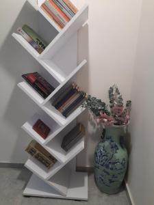 a white book shelf with a vase and books at Apartament Tade in Sopot