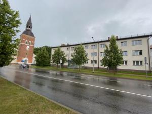 una calle de la ciudad con un edificio y una torre del reloj en Rīgas ielas apartamenti 1, en Valmiera