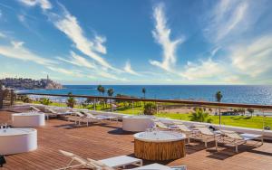 eine Terrasse mit weißen Stühlen, Tischen und Meerblick in der Unterkunft Brown Brut Seafront Hotel, a member of Brown Hotels in Tel Aviv