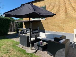 a patio with an umbrella and a couch and chairs at Enna in Landskrona