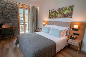 una camera da letto con un grande letto e un muro in pietra di Quinta Vale Vitis a São Vicente