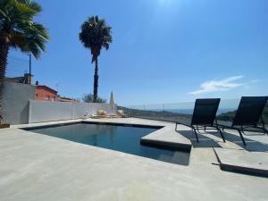 uma piscina com duas cadeiras e uma palmeira em Ece Golden Villa Amazing 4 bedroom vila with pool em Alella
