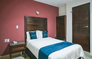 1 dormitorio con cama grande y pared roja en Hotel Granda Inn, en Tuxtla Gutiérrez