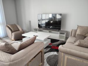 salon z 2 krzesłami i telewizorem w obiekcie Grand et superbe appartement proche Paris w mieście Creil