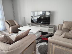 a living room with two chairs and a tv at Grand et superbe appartement proche Paris in Creil