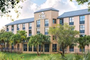 un edificio de oficinas con palmeras delante en The Palms Inn & Suites Miami, Kendall, FL en Kendall