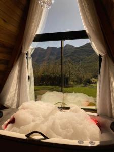 a tub with a view of a mountain from a window at Vista dos Canyons in Praia Grande