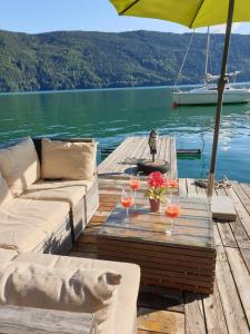 a table with wine glasses and an umbrella on a dock at DasHausAmSee in Döbriach