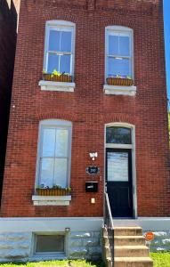 a red brick building with two windows and flowers in window boxes at Old North Shanty in Saint Louis