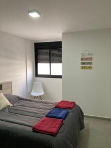 ein Schlafzimmer mit einem Bett mit roten und blauen Handtüchern darauf in der Unterkunft Brasil flats-Nueva Cordoba in Cordoba